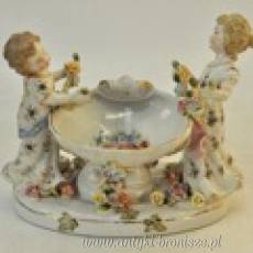 Puchar z porcelany (polichromia) w formie muszli podtrzymywanej przez 2 dziewczynki. (apocryphe). H 18 x 22cm - poz. 5142